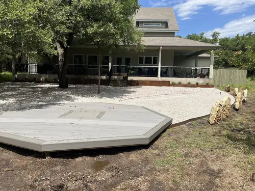 Octagonal composite deck platform finished on a gravel base behind a Hill Country home