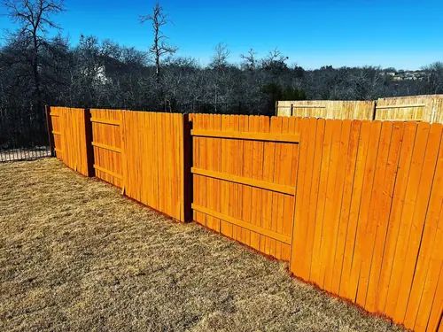 Freshly stained privacy fence panels running along a back property line