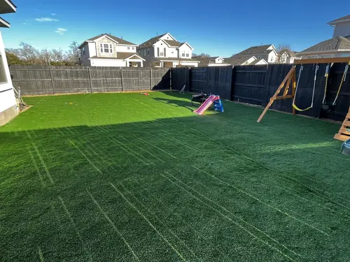 Full back-yard artificial turf installation laid around a children's play set