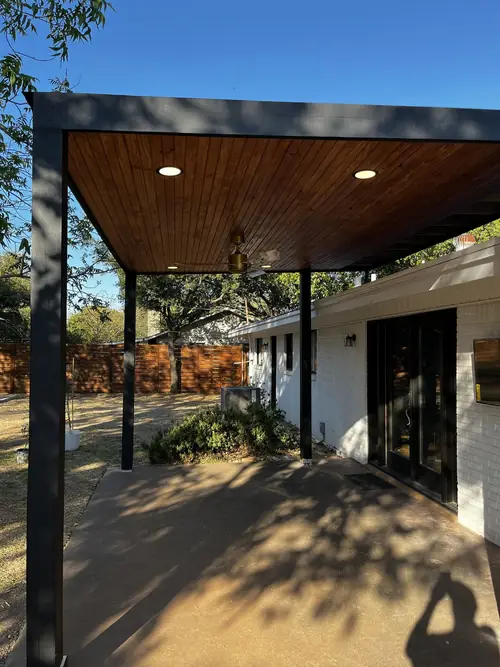Steel-framed patio cover with a stained tongue-and-groove wood ceiling and recessed lighting