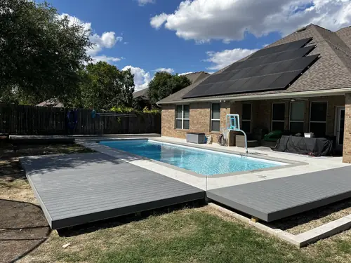 Twin composite deck platforms framing a backyard pool under a clear Texas sky